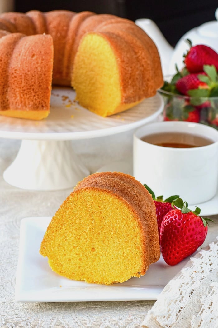 Wide shot photo of a single slice of custard bundt cake with full cake in the background