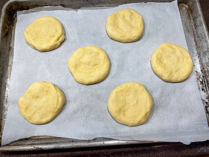 How to make the best hamburger buns photo showing buns with final stretch on a parchment lined baking sheet