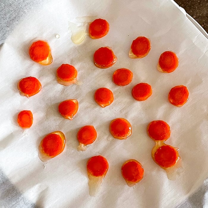 Using a fork lift each carrot slice onto a piece of parchment paper or wax paper