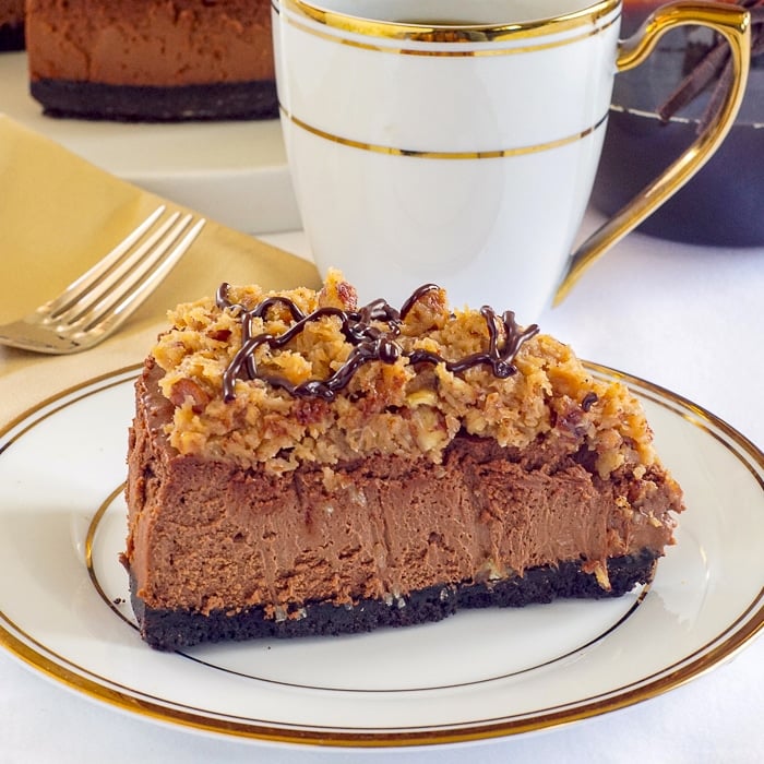One slice of German Chocolate Cheesecake on a white and gold coffee service
