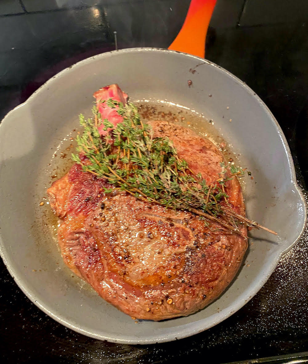 adding herbs to the seared steak