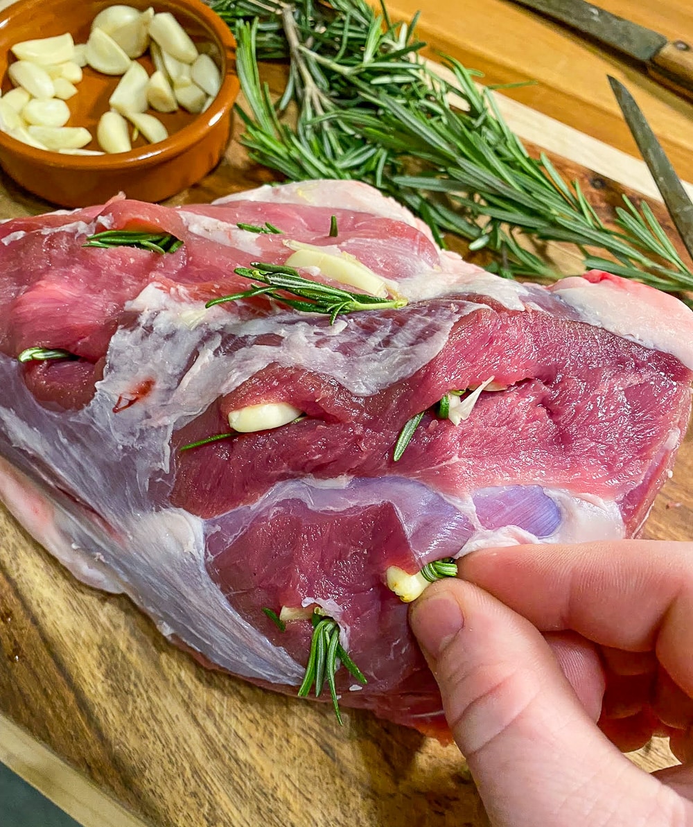 Pushing the garlic and rosemary into the meat