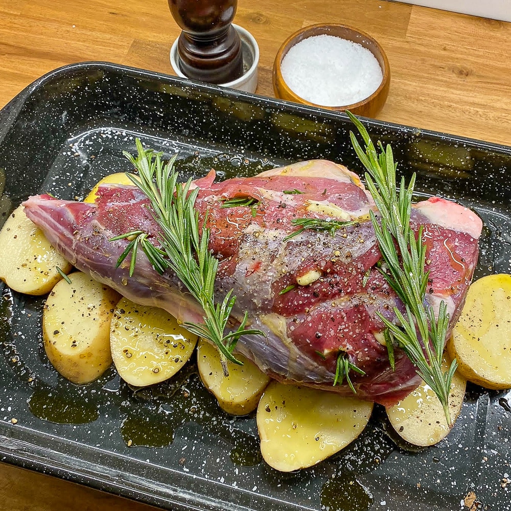 Roast Leg of Lamb on a bed of sliced potatoes, ready for the oven