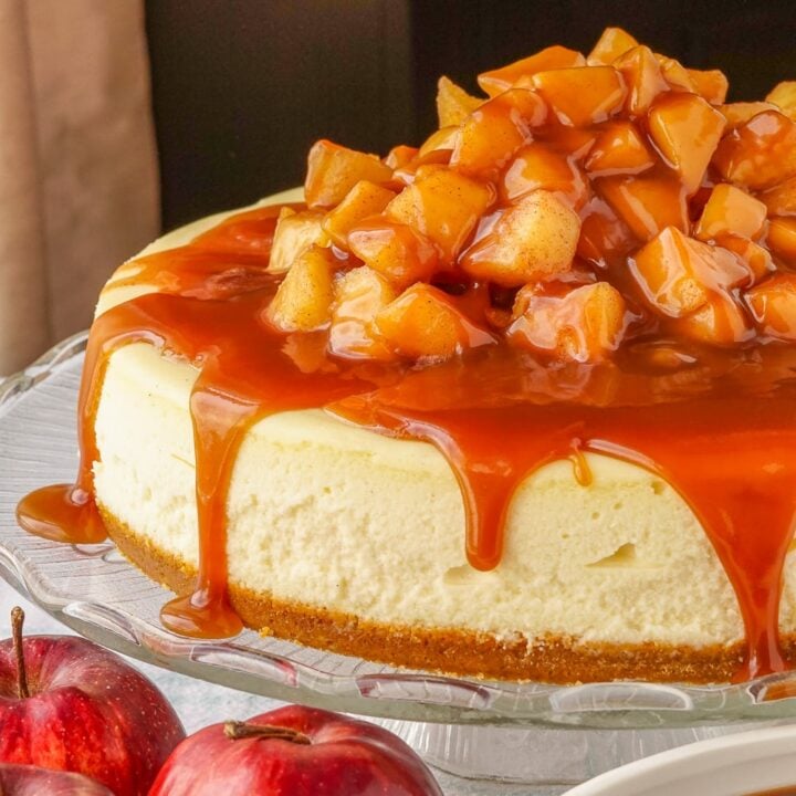 Caramel Apple Cheesecake uncut on a glass pedestal.