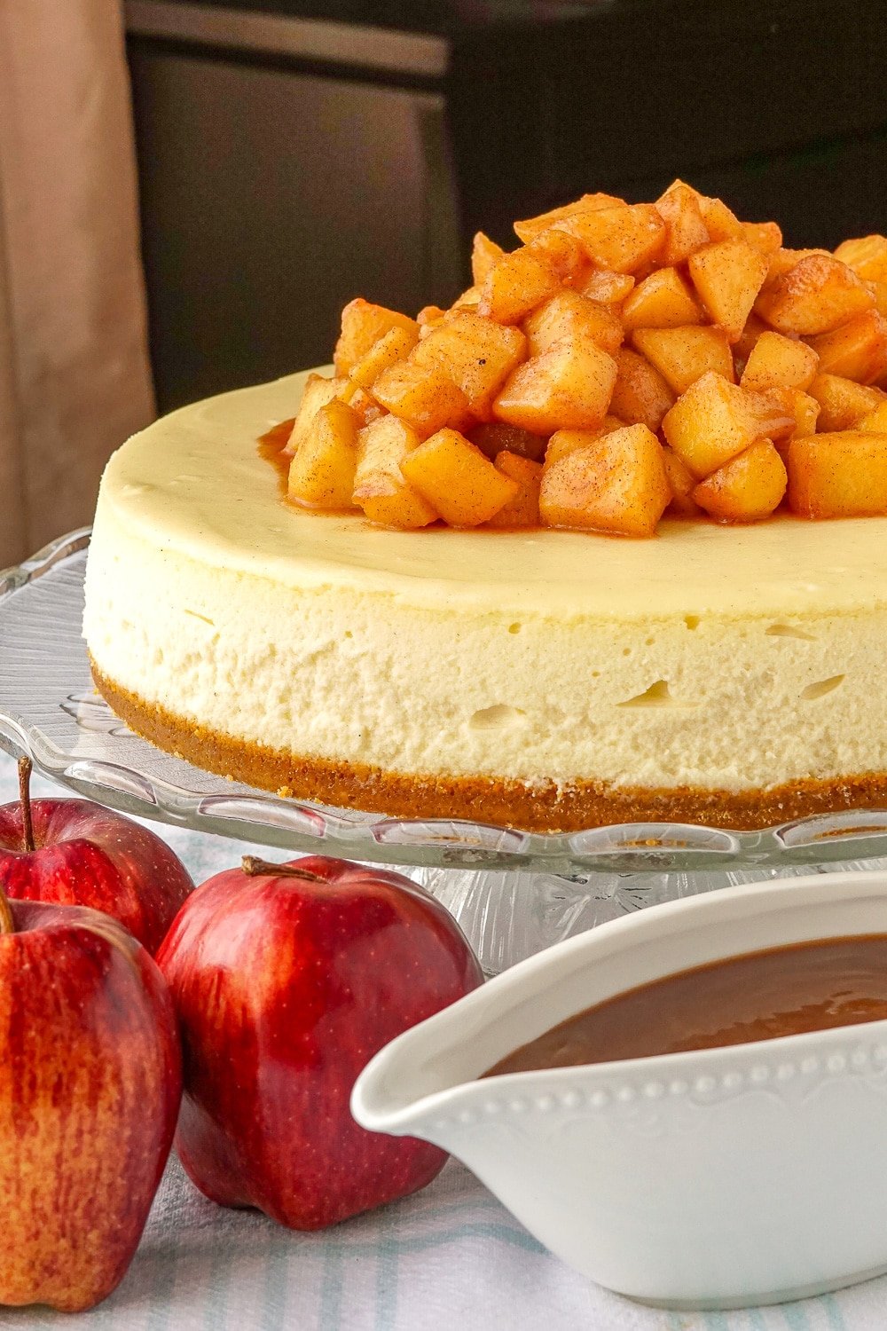 Caramel apple cheesecake shown with apples and caramel sauce