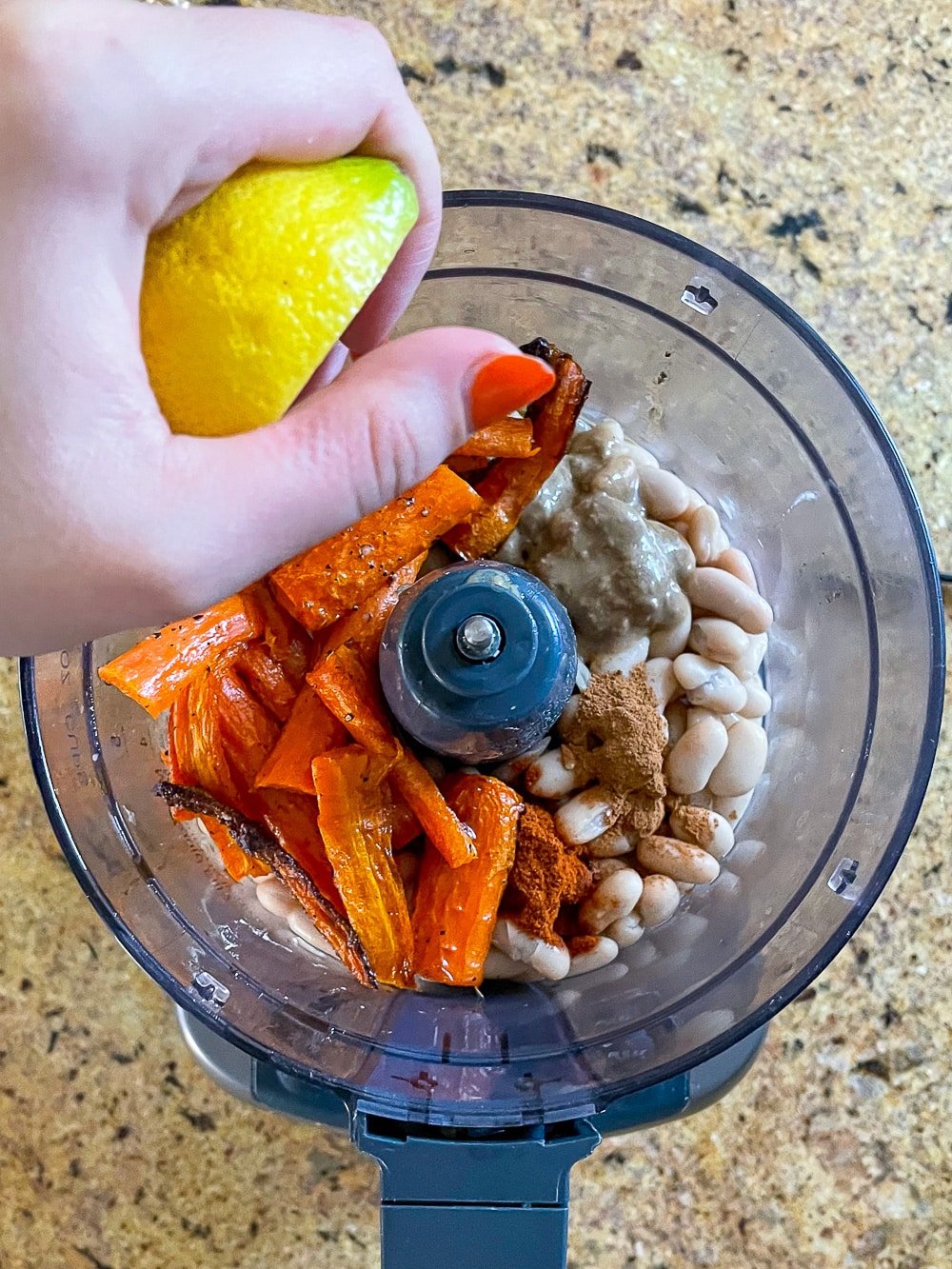 Squeezing lemon into roasted carrot hummus.