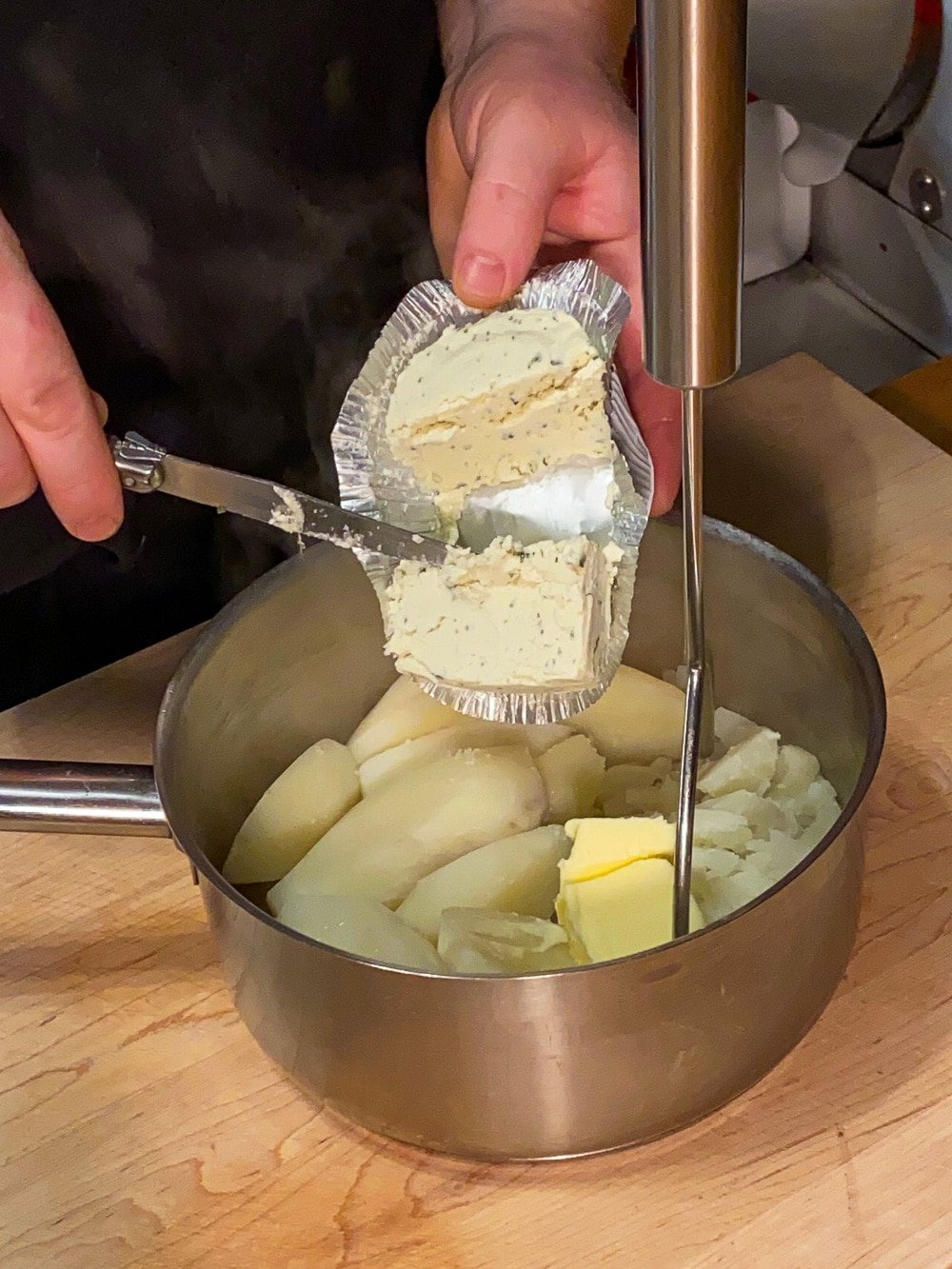 Adding the Boursin cheese to the mashed potatoes