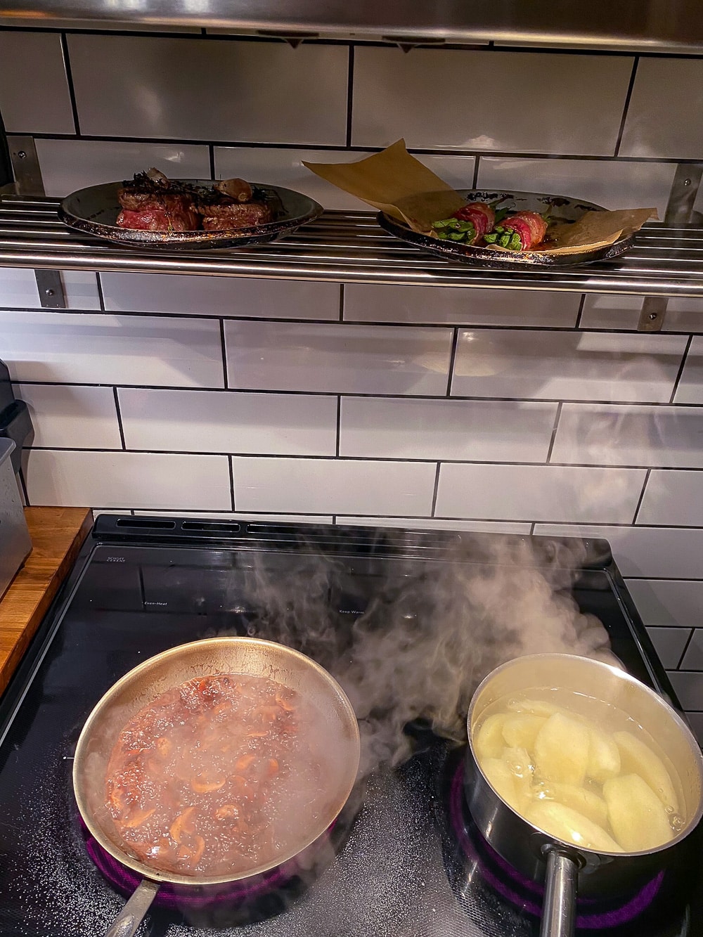Photo of cooking on stovetop with steaks resting in Marks kitchen