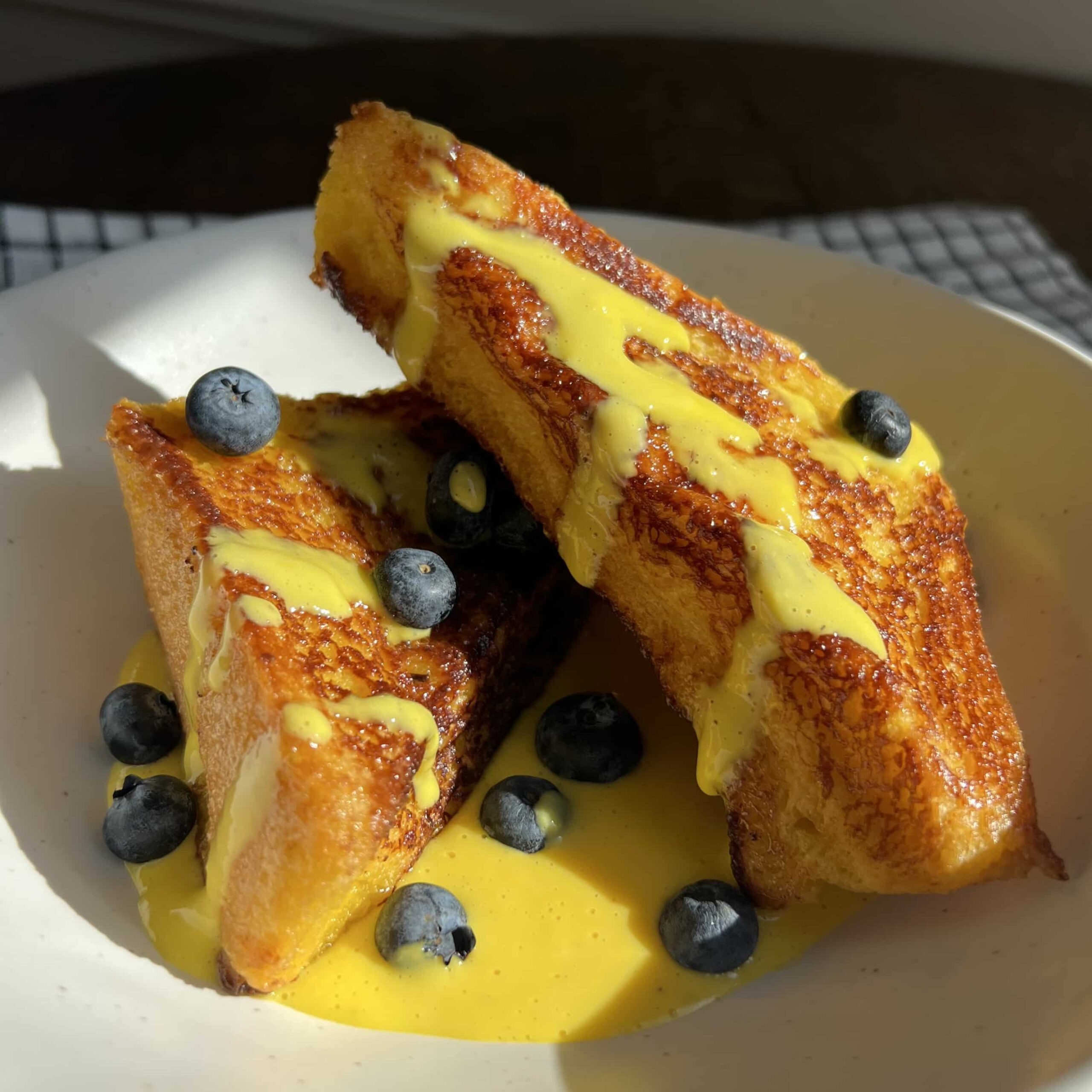 Spanish Torrijas with Creme Anglaise in aa bowl with blueberries.