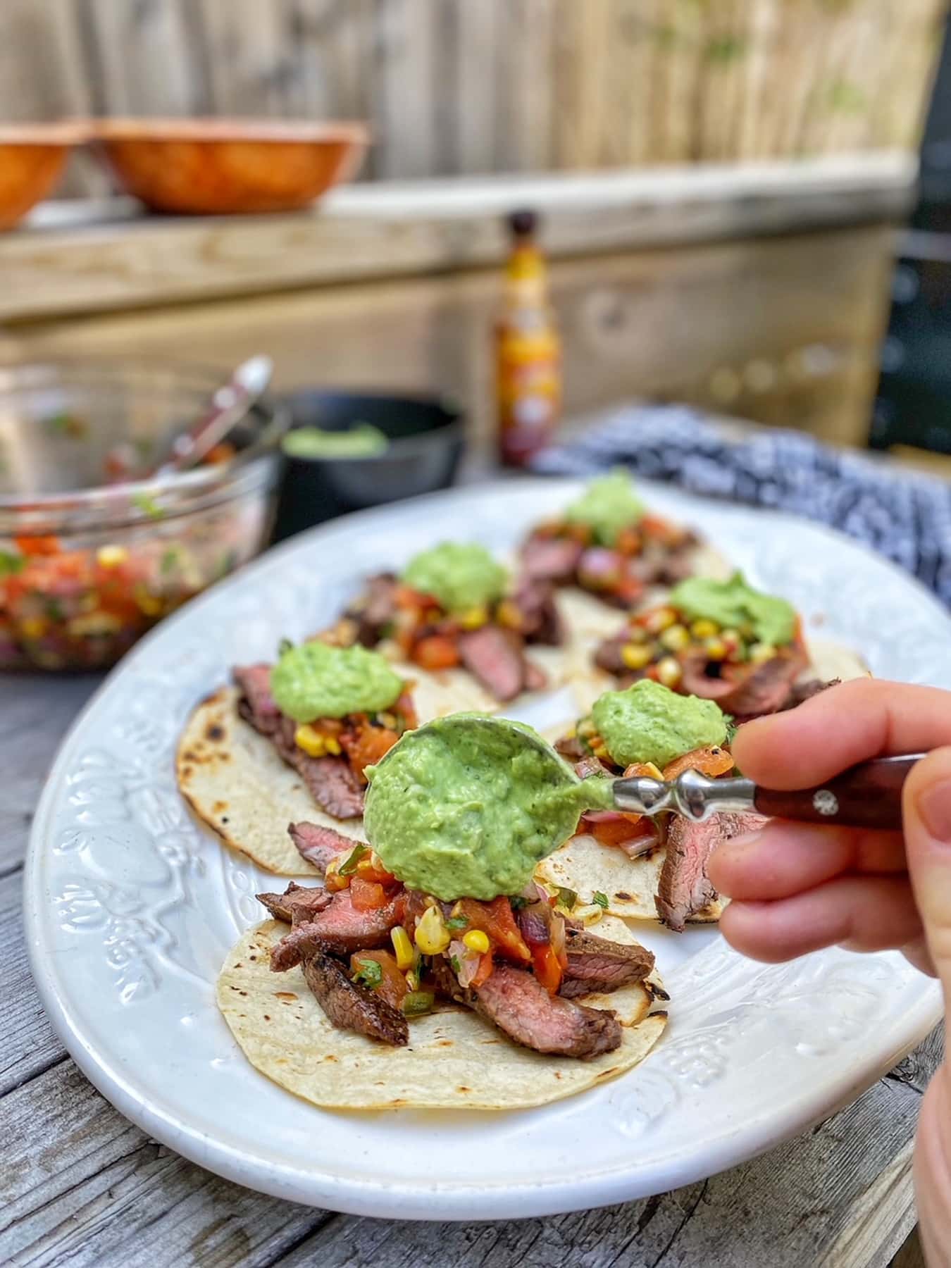 Adding the Avocado Crema to the Flank Steak Tacos with Grilled Salsa