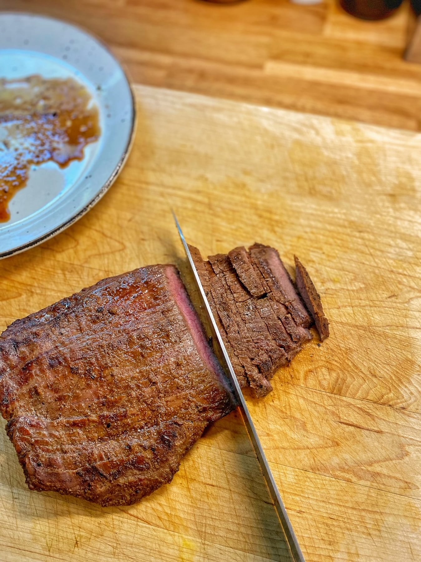Cutting across the grain is the proper way to slice the cooked flank steak