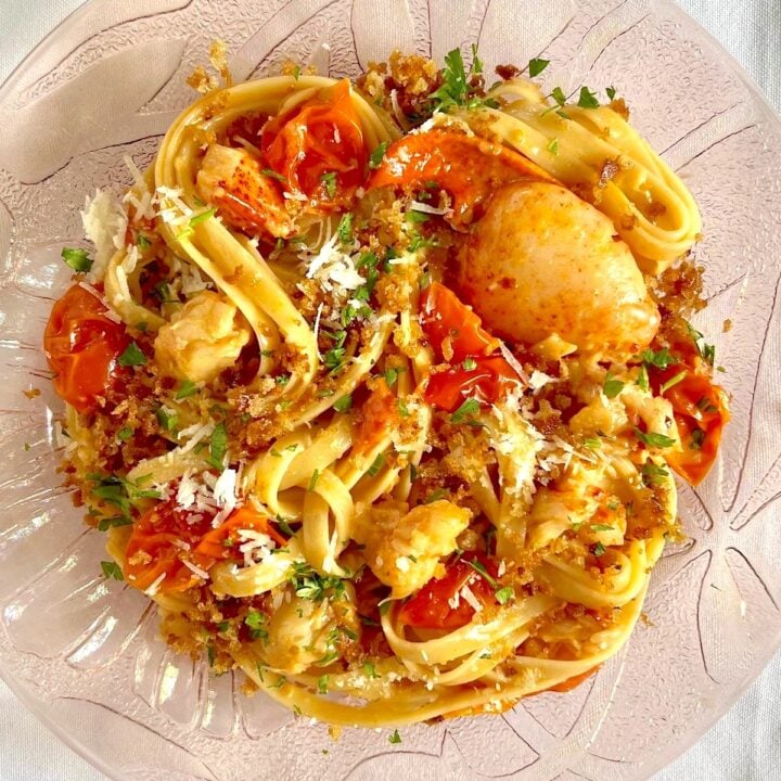 A plate of lobster pasta on a white tablecloth.