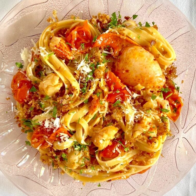 A plate of lobster pasta on a white tablecloth.