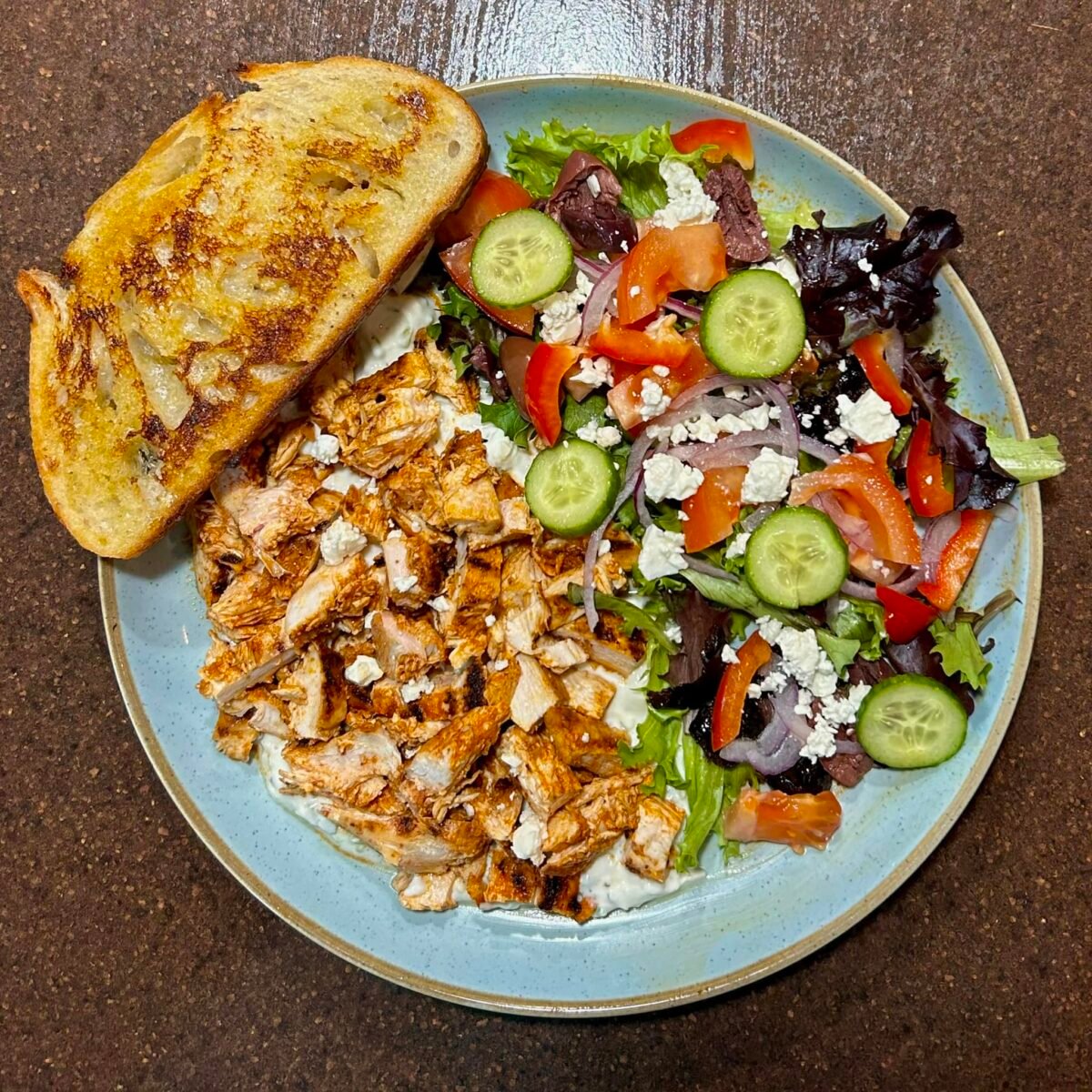 Chicken Souvlaki Salad with Lemon Mint Tzatziki close up shot on blue plate