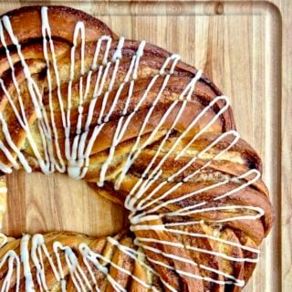 Close up photo of Cinnamon Roll Couronne on a wooden cutting board.