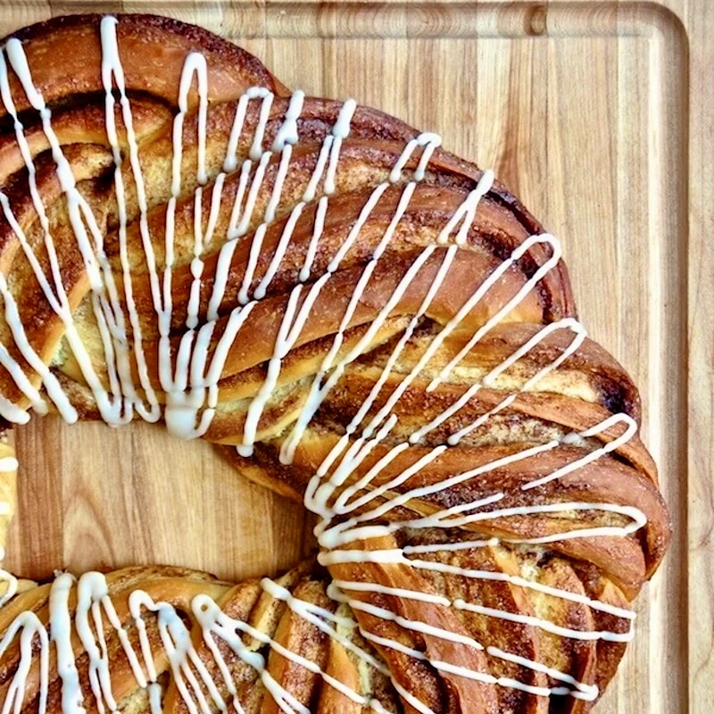 Close up photo of Cinnamon Roll Couronne on a wooden cutting board.