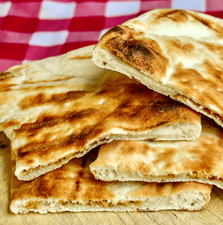 Coconut Cashew Raisin Naan photo of cooked naans on a wooden cutting board