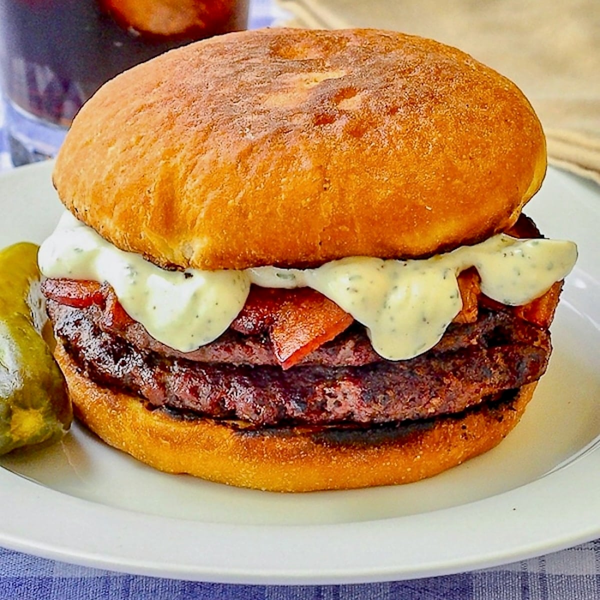 The Ultimate Newfie Touton Burger close up photo of burger on white plate with a dill pickle