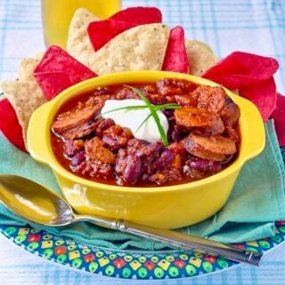 Smoked Sausage Chili in a yellow serving bowl with corn chips on the side