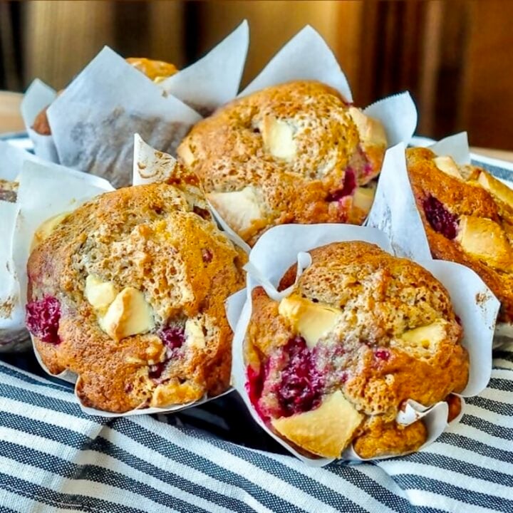 Banana Raspberry White Chocolate Muffins in a baket, square cropped for Google featured image.