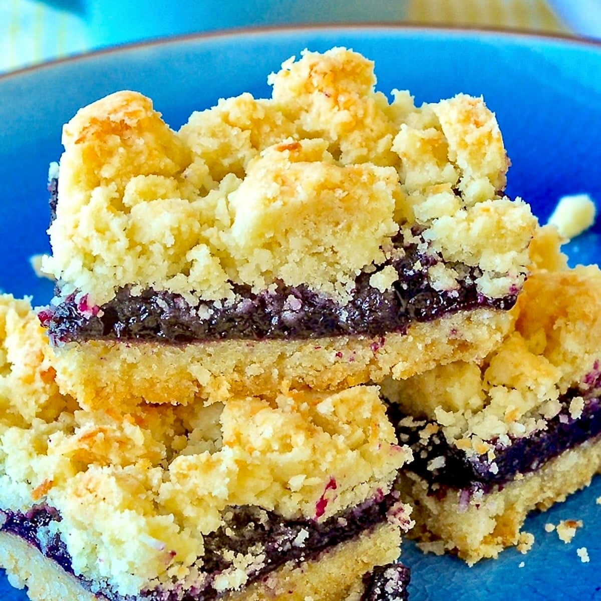 Blueberry Coconut Crumble Bars close up photo of cookie bars on a blue plate.