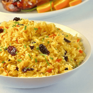 Featured image. carrot Raisin Rice Pilaf in a white serving bowl