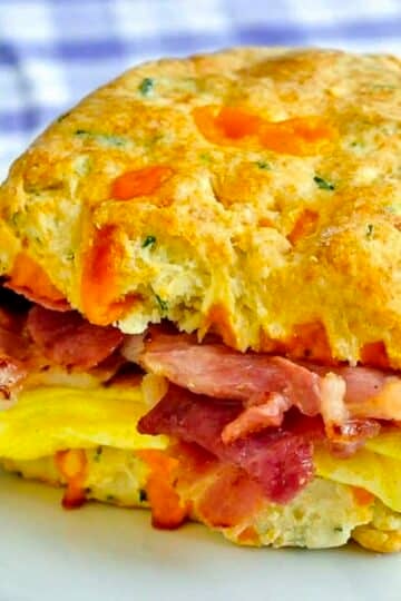 Ham Cheddar Biscuit Breakfast Sandwiches close up photo of one sandwich in a white plate.