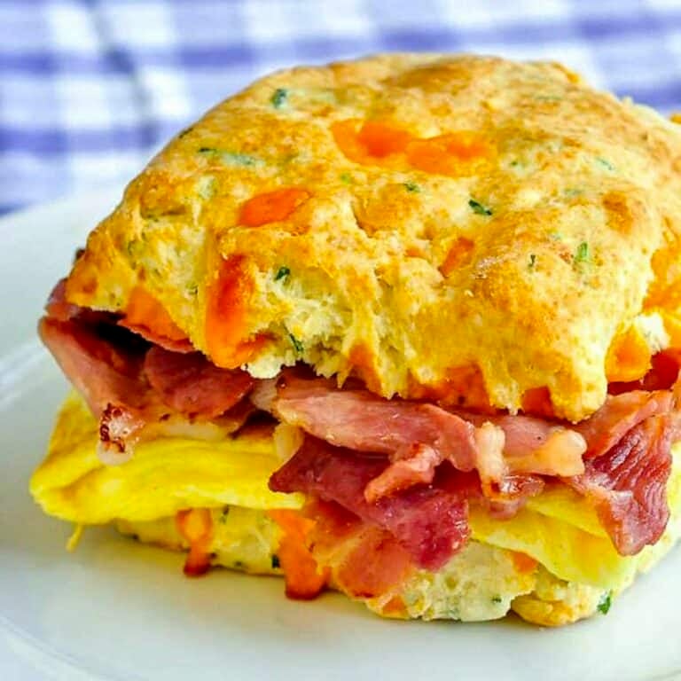 Ham Cheddar Biscuit Breakfast Sandwiches close up photo of one sandwich in a white plate.