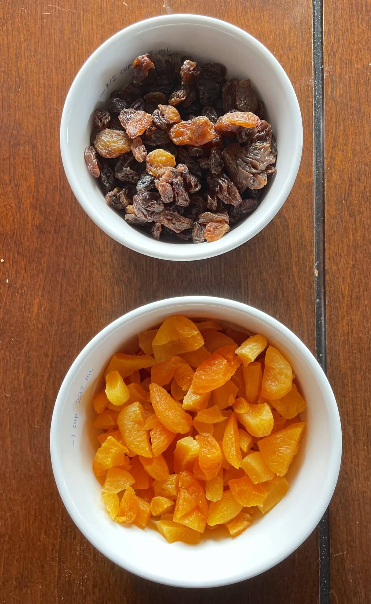 Chopped apricots and raisins in white bowls