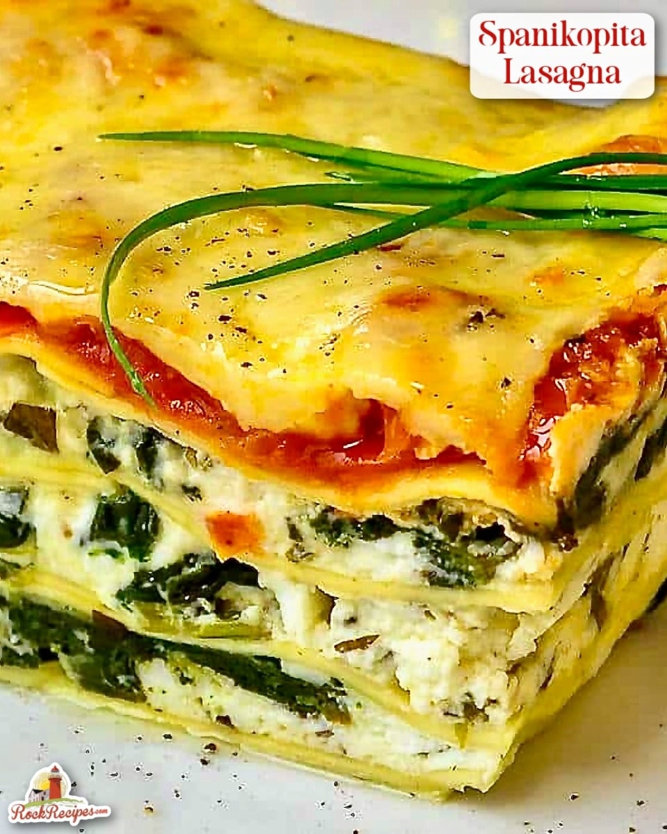 Spanakopita Lasagna close up photo of one serving on a white plate with chive garnish on top. Photo has title text and Rock Recipes logo added for Pinterest and social media posts.