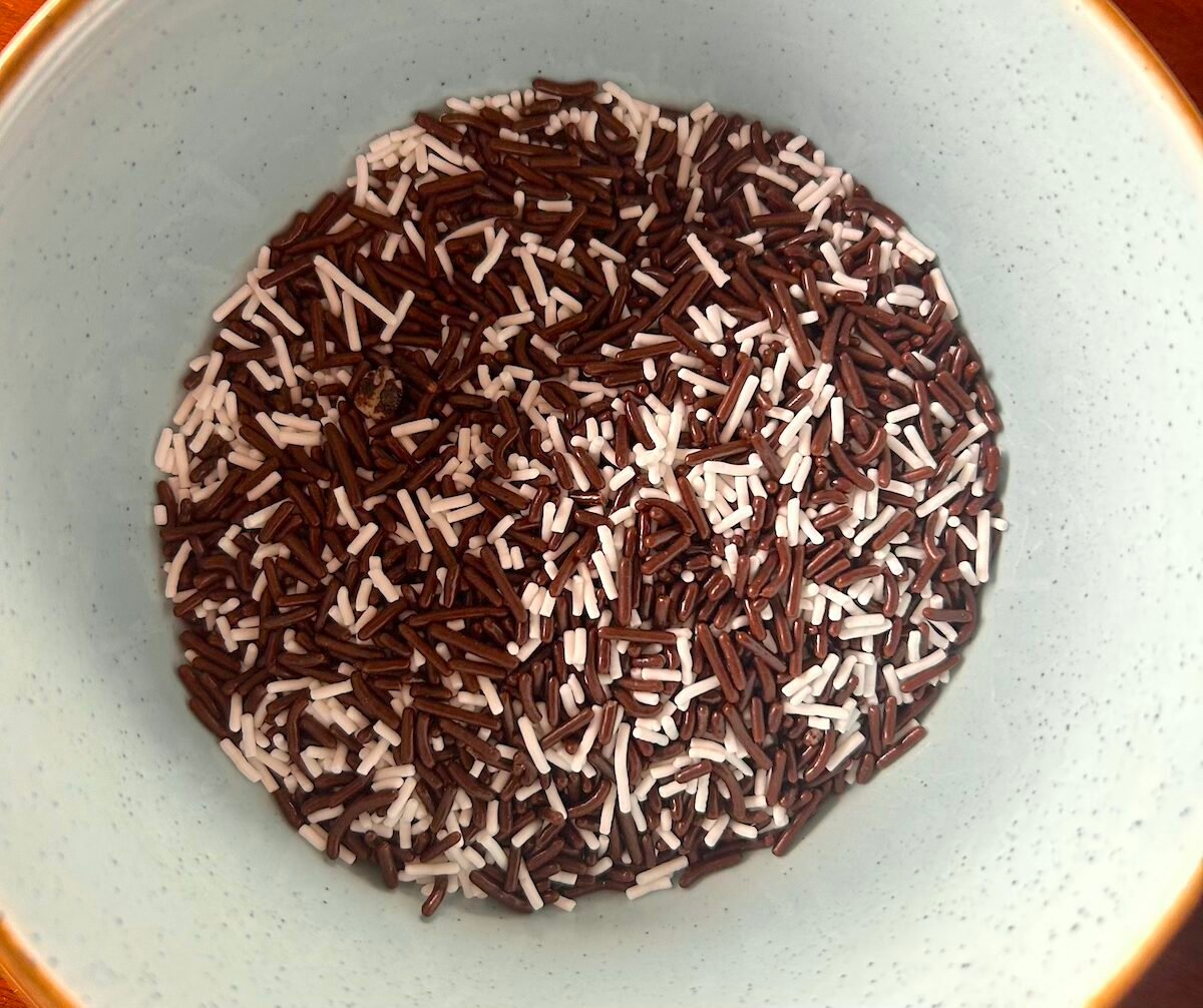 Chocolate and vanilla candy jimmies in a blue bowl