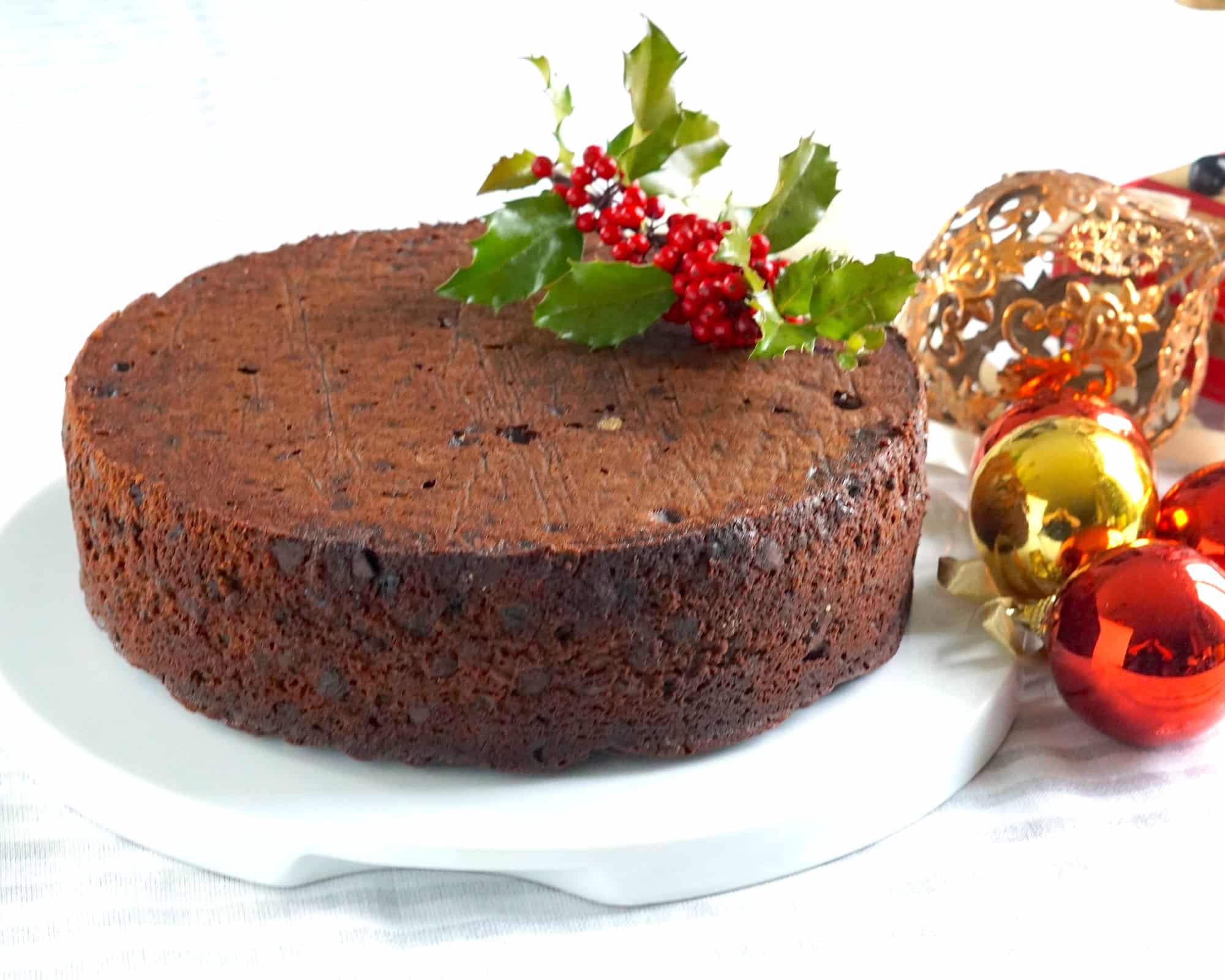 Chocolate Cherry Fruitcake close up photo of the whole on a white plate with Christmas decorations