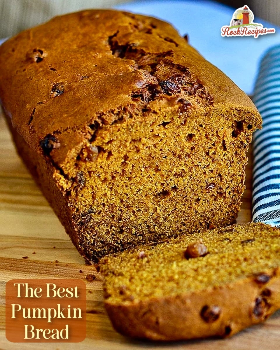 Close up photo of Pumpkin Bread with first slice cut, shown on wooden cutting board. Title text haas been added for Pinterest and social media posts.