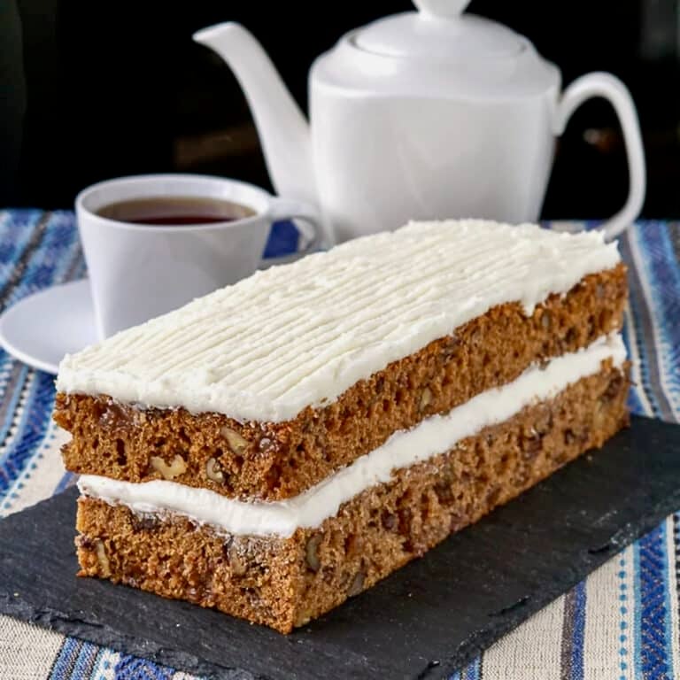 Spanish Bar Cake on a slate serving plate with coffee in the background.