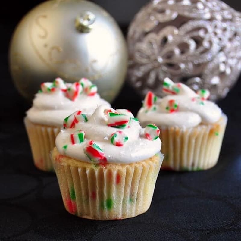 3 Candy Cane Cupcakes on a black background with christmas decorations.