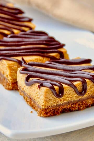 Gingersnap Pumpkin Cheesecake Bars close up photo of bars on a white platter