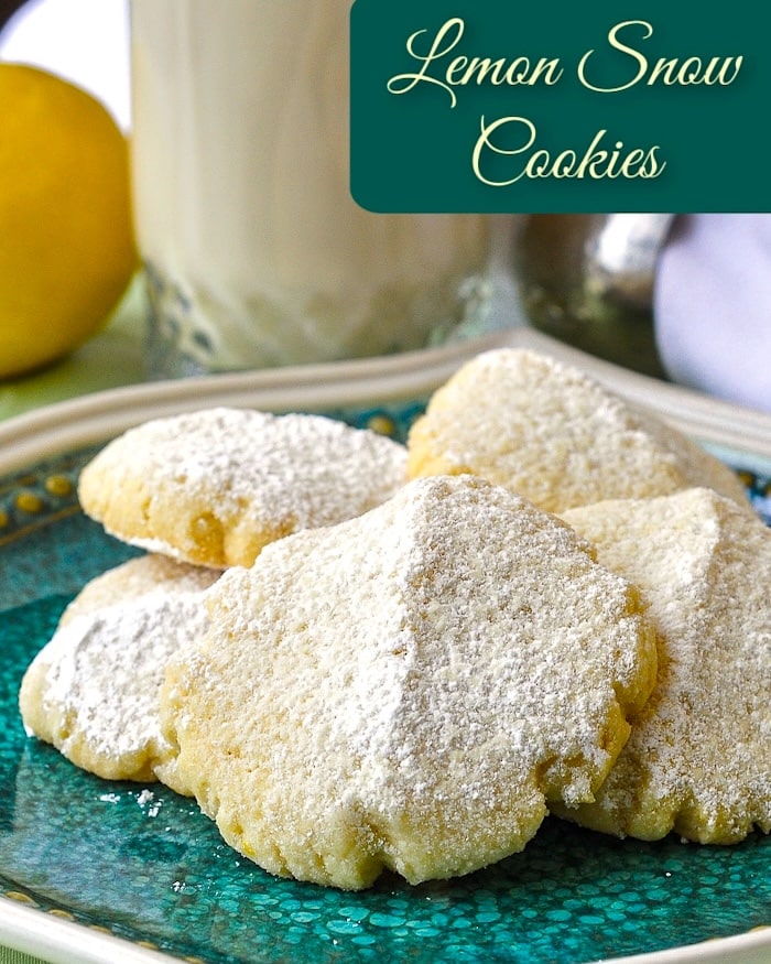 Lemon snow cookies on a green plate with title text added for social media.