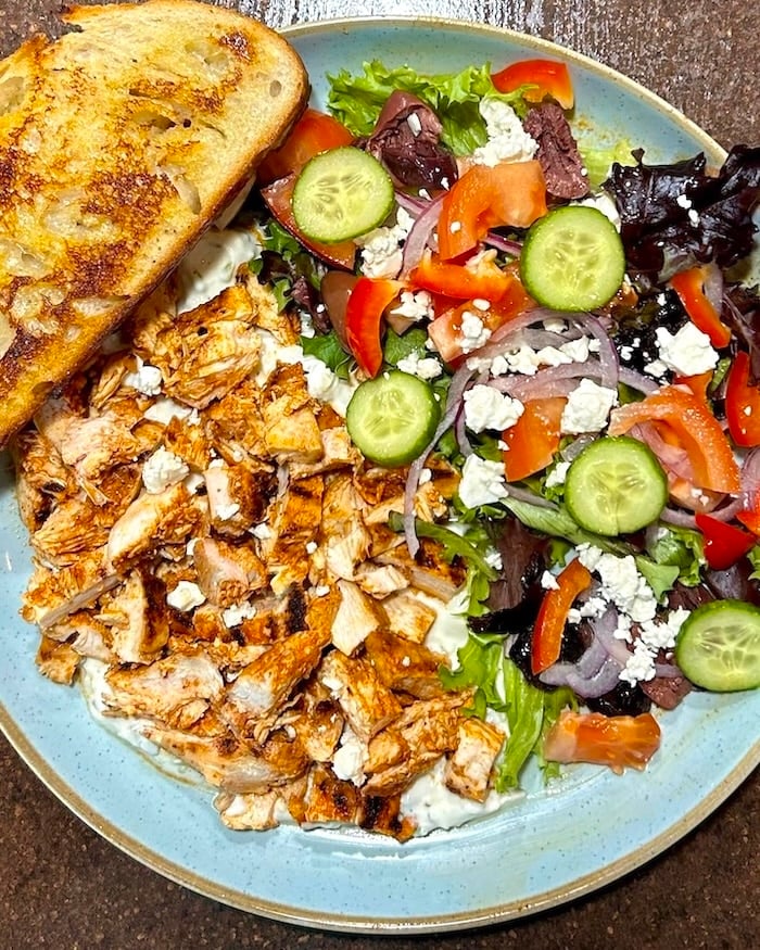 Chicken Souvlaki Salad with Lemon Mint Tzatziki close up shot on blue plate