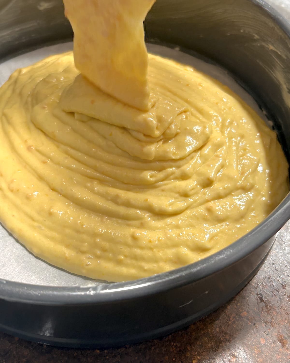 batter being poured into a springform pan.