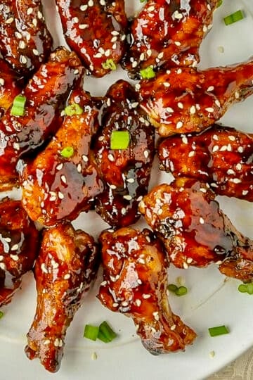 Glazed Teriyaki Chicken Wings close up photo on white plate for Google featured image.