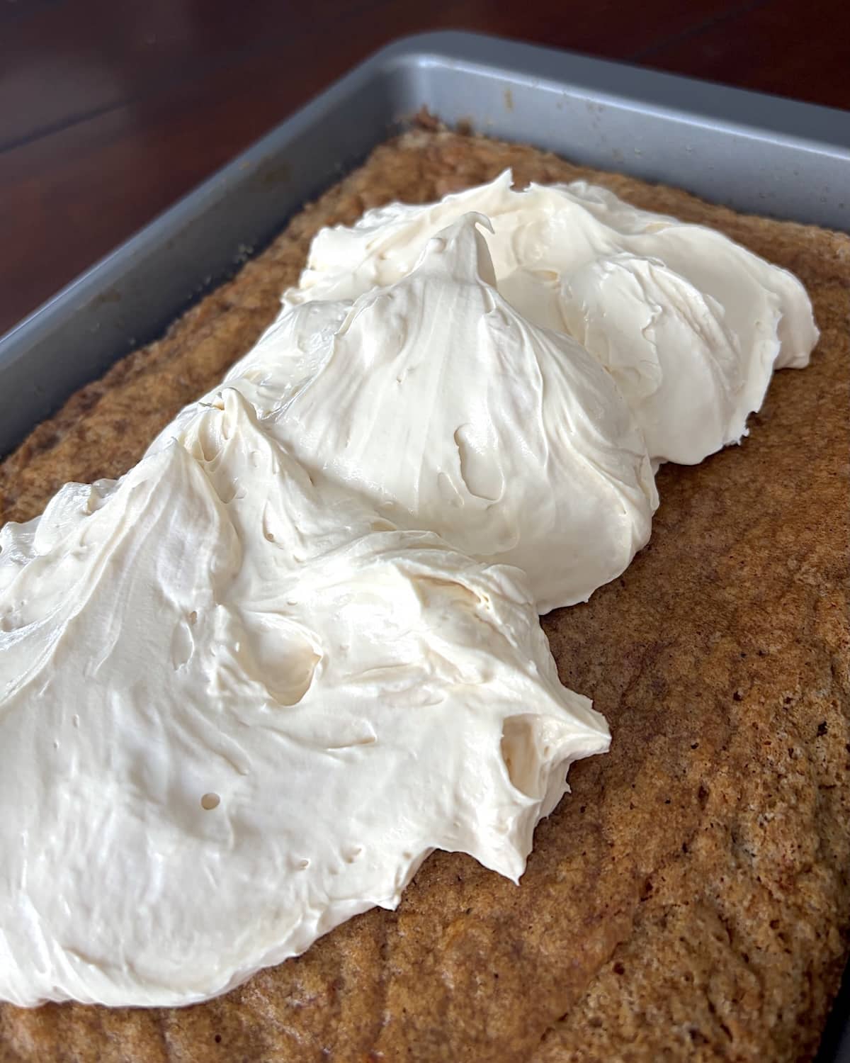 Whipped Cheesecake Frosting being added to a slab cake.