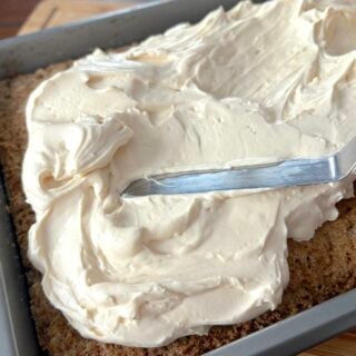 Whipped Cheesecake Frosting being spread on a slab carrot cake.