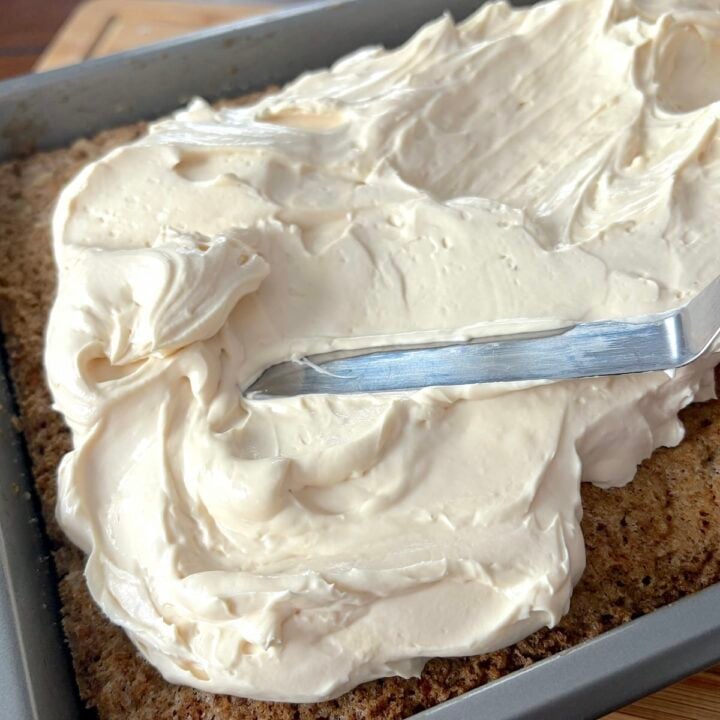 Whipped Cheesecake Frosting being spread on a slab carrot cake.