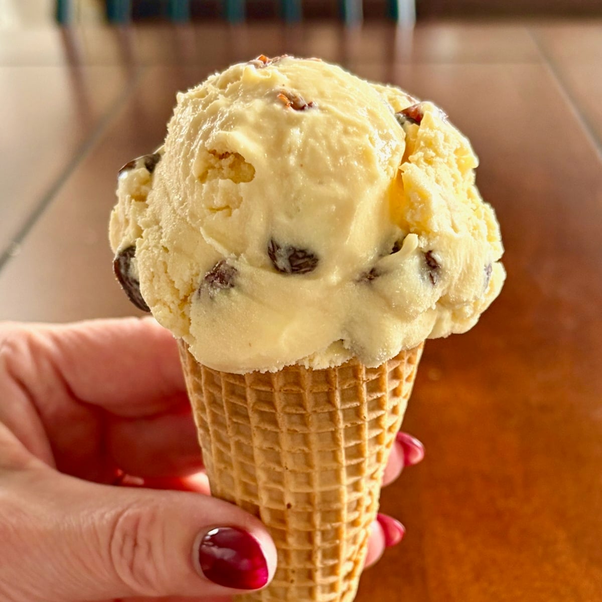 Close up photo of a scoop of Rum Raisin Ice Cream pictured in a sugar cone.