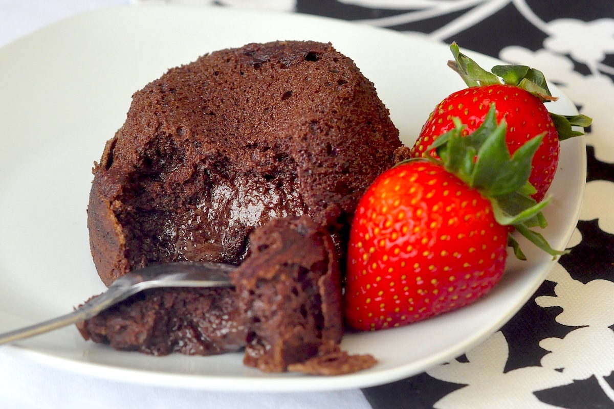 Molten Chocolate Mousse Cake wide shot photo on a white plate with strawberries