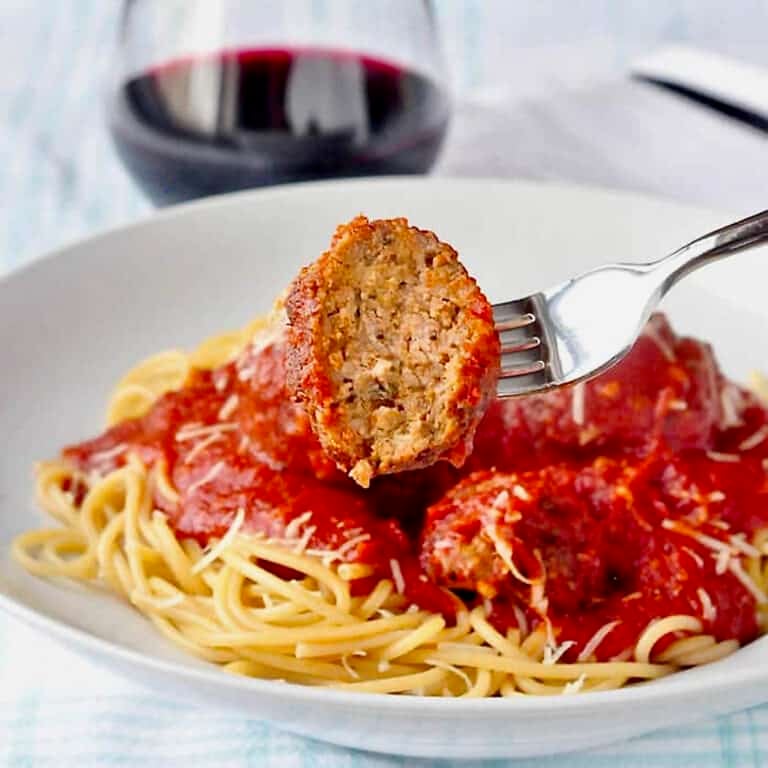 The Best Spaghetti and Meatballs close up photo of a meatball with a bite taken out.