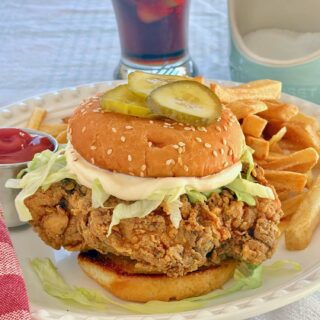Copycat Big Mary Chicken Sandwich photo of completed sandwich with french fries in the background.