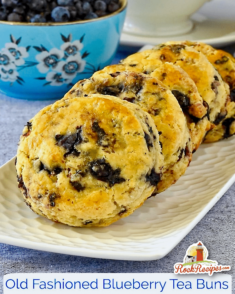 Blueberry Tea Buns on a white plate with blueberries in background with title text added for social media posts.