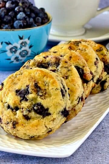 Blueberry Tea Buns on a whote rectangular serving pate with berries and butter in the background