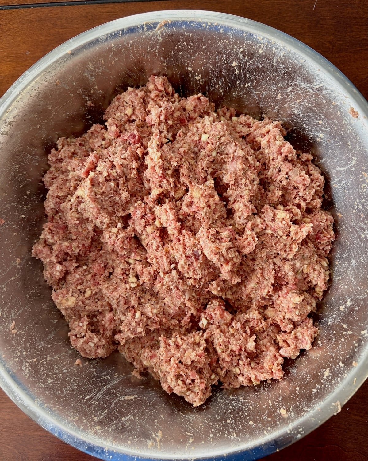 Photo of hand in disposable gloves mixing the mini meatballs mixture.